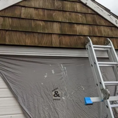 Wooden shingles on a garage with sheet covering garage door to stop paint drips