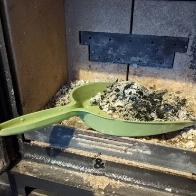 Dustpan in a wood burning stove removing excess amounts of ash