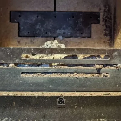 Firebox grate filled with ash showing how much ash should be left in a wood burning stove