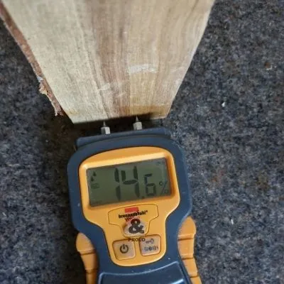 Using a moisture meter to check how dry a piece of firewood is